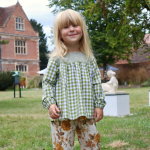 smiling girl wearing an olive green gingham blouse with long sleeves