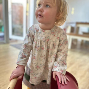 Child wearing handmade cream floral blouse in cotton poplin, slow fashion sustainable kidswear styled with a wool skirt
