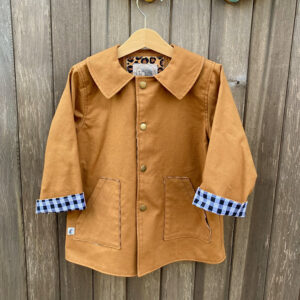 Handmade children’s lightweight rust coloured cotton canvas coat with collar, popper fastening and black and white gingham lining.