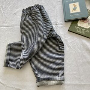 Classic blue and white striped denim kids trousers displayed as a flat lay with books