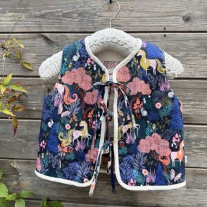 handmade toddler gilet in a fantasy unicorn forest design on a navy background. Fastens with three ties at the front