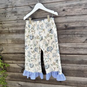 Girls floral trousers with blue striped frill hem and elastic waistband, handmade from vintage-style fabric.